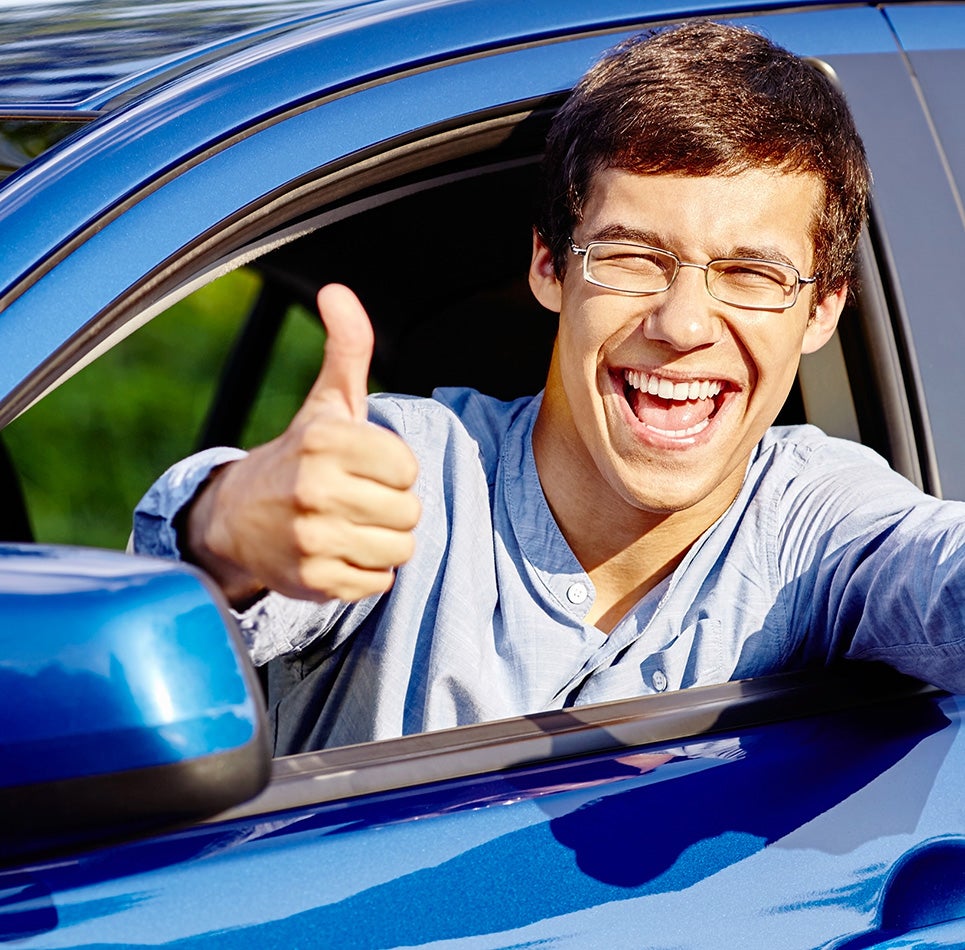 Man smiling in car giving a thumbs up